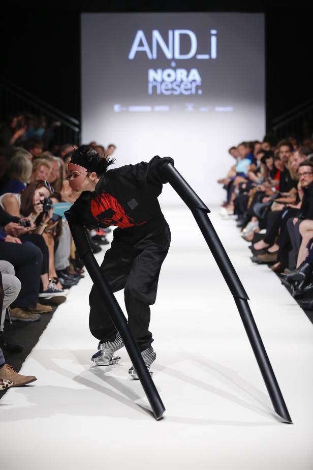 Eine Person in ungewöhnlicher Kleidung und Maske läuft über einen Laufsteg.