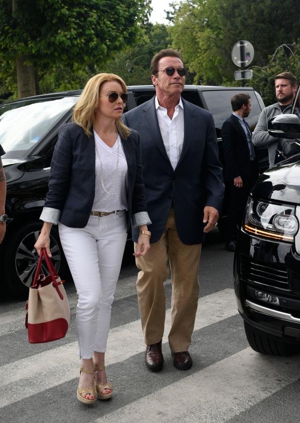 Arnold Schwarzenegger und eine Frau überqueren eine Straße.