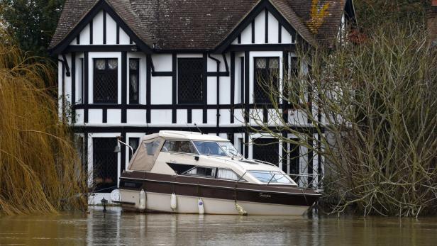 Ein Boot steht vor einem Haus im Wasser, möglicherweise aufgrund von Überschwemmungen.