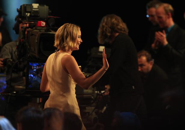 Jennifer Lawrence winkt vor einem Publikum und Fernsehkameras.
