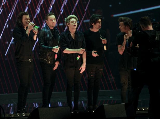 Die Band One Direction steht auf einer Bühne und singt.