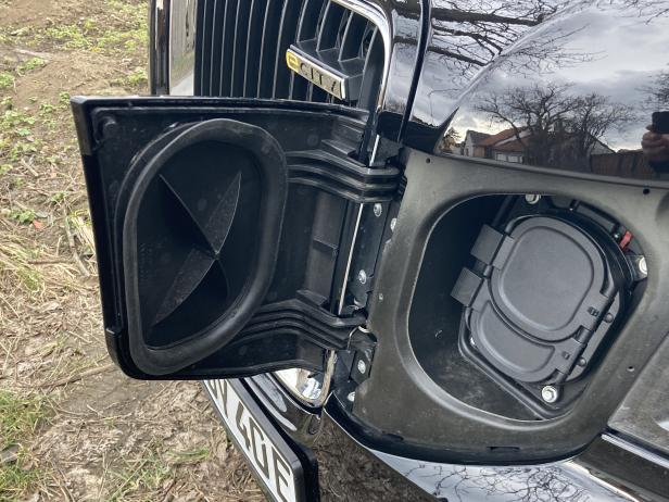 Die geöffnete Ladeklappe eines schwarzen Elektroautos mit dem Schriftzug „eCITY“.