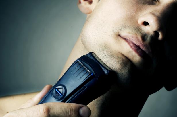 Ein Mann rasiert sich mit einem elektrischen Rasierer den Bart.