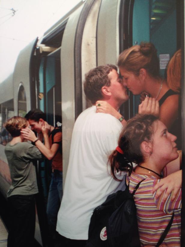 Mehrere Paare küssen sich am Eingang eines Zuges.