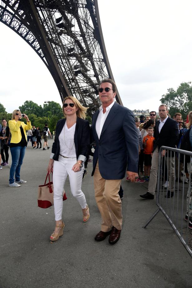 Arnold Schwarzenegger und eine Frau gehen vor dem Eiffelturm entlang.