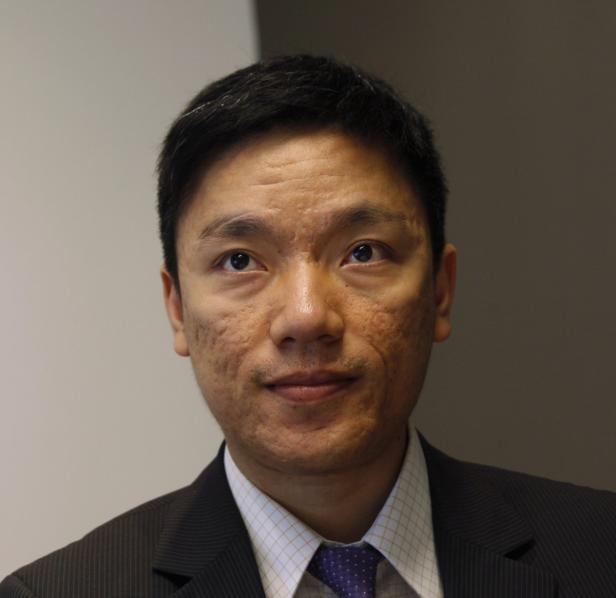 Ein Mann mit dunklen Haaren und Anzug blickt in die Kamera.