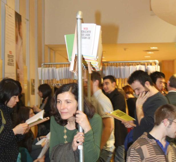 Menschen stehen in einem Raum und lesen Broschüren.