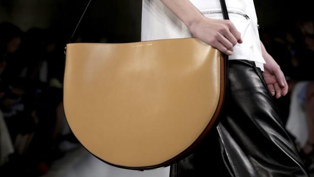 Eine Person trägt eine große, hellbraune Ledertasche über der Schulter.