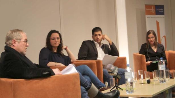 Vier Personen sitzen in Sesseln bei einer Podiumsdiskussion.