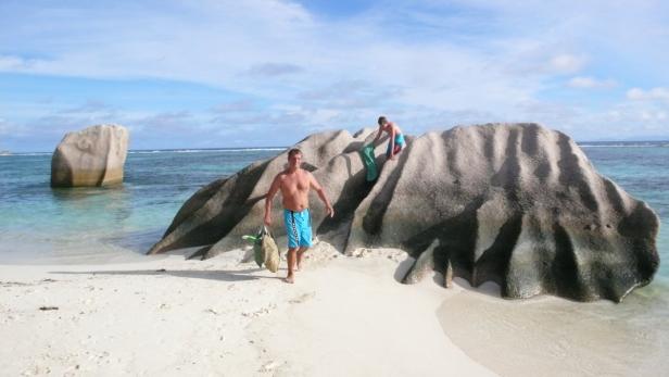 Zwei Männer an einem Strand mit großen Felsen im Wasser.