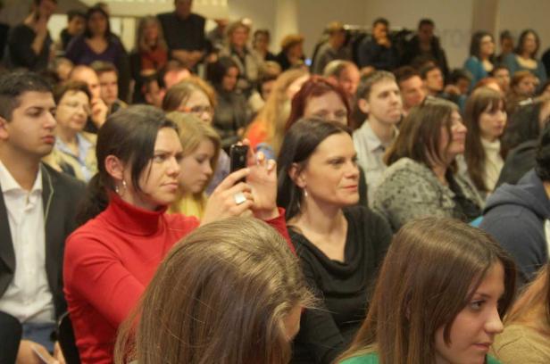 Ein Publikum sitzt bei einer Veranstaltung und hört aufmerksam zu.