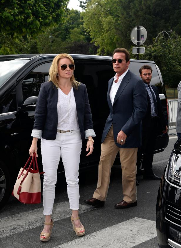 Arnold Schwarzenegger und eine Frau verlassen ein schwarzes Auto.