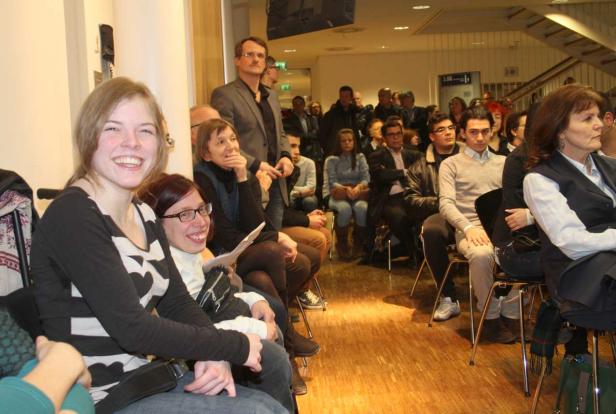 Zuschauer sitzen bei einer Veranstaltung in einem Raum.