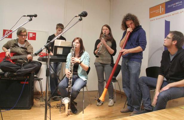 Eine Musikgruppe spielt auf verschiedenen Instrumenten, darunter Bass, Klarinette und Didgeridoo.