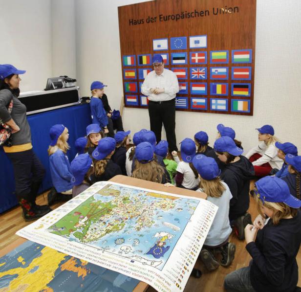 Eine Gruppe Kinder mit blauen Kappen betrachtet eine Karte der Europäischen Union.