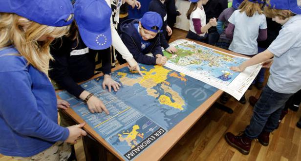 Eine Gruppe von Kindern betrachtet eine Karte des Euroraums.