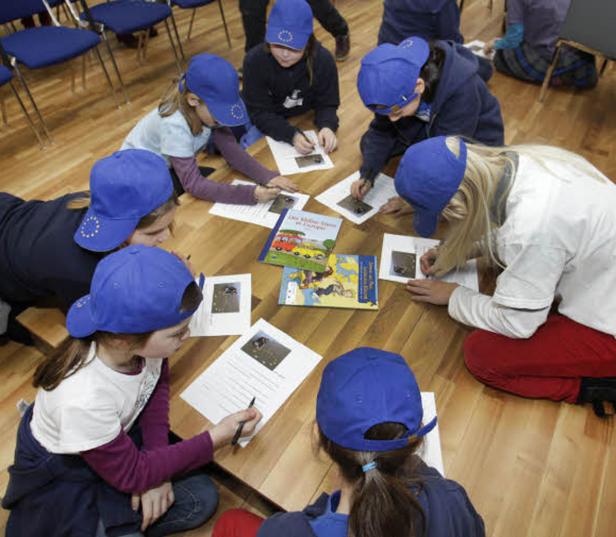 Eine Gruppe Kinder sitzt um einen Tisch und bearbeitet Aufgaben zum Thema Europa.