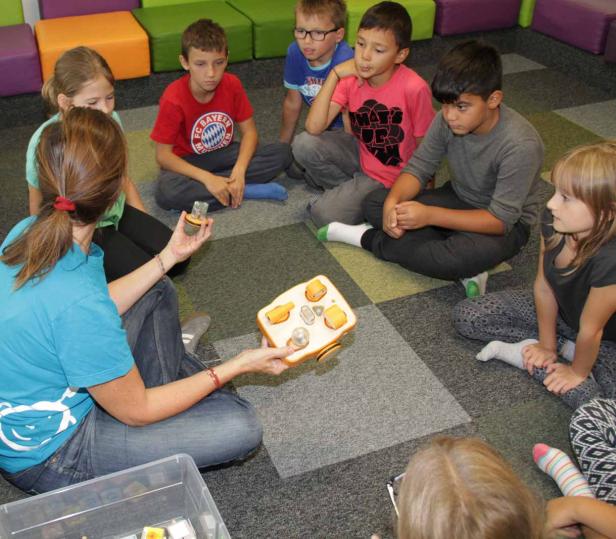 Eine Lehrerin zeigt einer Gruppe von Kindern ein Lernspielzeug.