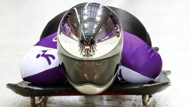 Ein Skeleton-Athlet mit österreichischem Helm liegt auf seinem Schlitten.