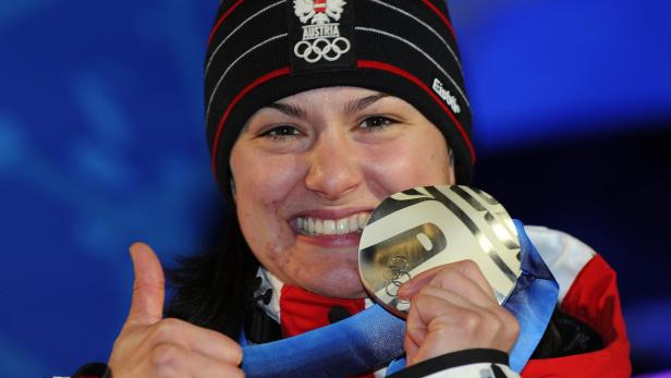 Eine österreichische Athletin mit Mütze und Olympia-Medaille zeigt den Daumen nach oben.