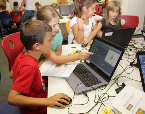 Eine Gruppe Kinder arbeitet an Laptops in einem Klassenzimmer.