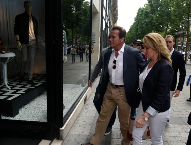 Arnold Schwarzenegger und eine Frau gehen an einem Schaufenster vorbei.