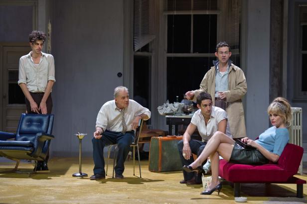 Szene aus einem Theaterstück mit fünf Schauspielern auf einer Bühne.