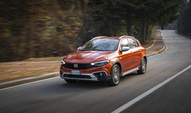 Ein orangefarbener Fiat Tipo Cross fährt auf einer kurvenreichen Straße.