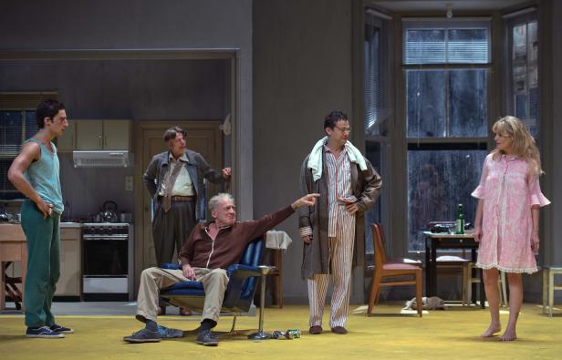 Szene aus einem Theaterstück mit fünf Schauspielern in Alltagskleidung.