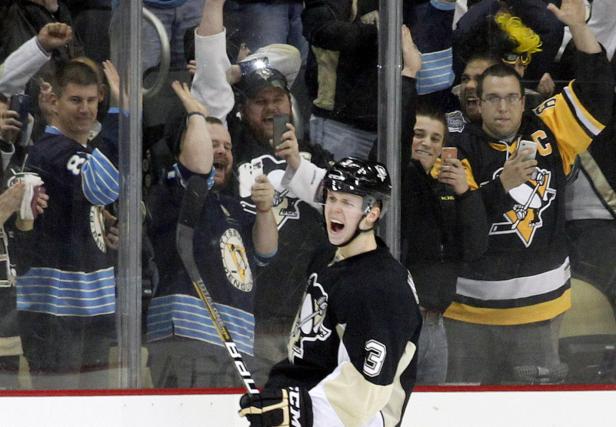 Ein Eishockeyspieler jubelt vor einer jubelnden Menge Fans.