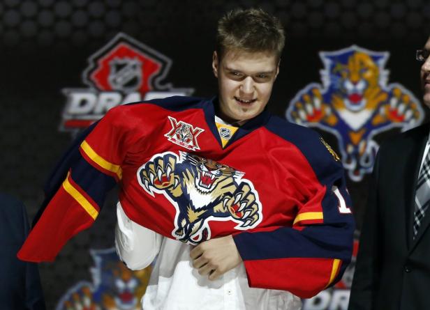 Ein junger Mann zieht ein Trikot der Florida Panthers über ein Hemd.