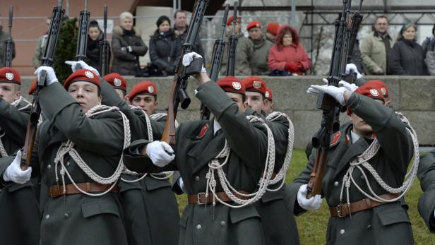 Soldaten in Uniform mit roten Baretts präsentieren Gewehre.