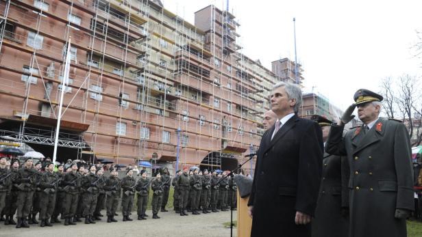 Eine Gruppe Soldaten steht vor einem Gerüstbau und salutiert.