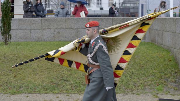 Ein Soldat in Uniform trägt eine große, verzierte Fahne.