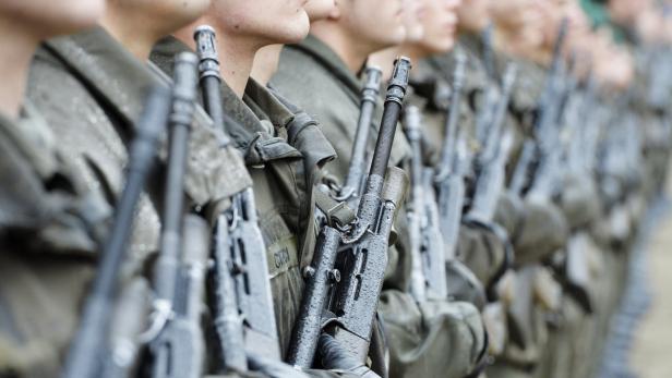 Eine Reihe von Soldaten in Uniform mit Gewehren im Anschlag.