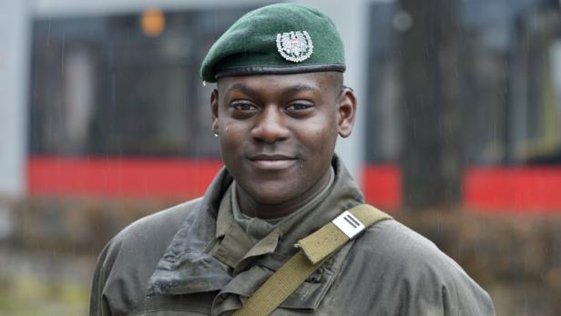 Ein junger Mann mit grüner Militärberet und Uniform im Regen.