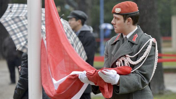 Ein Soldat in Uniform faltet die österreichische Flagge.