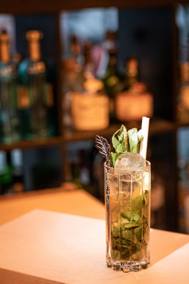 Ein Cocktail mit Eis und Minze steht auf einer Bar.