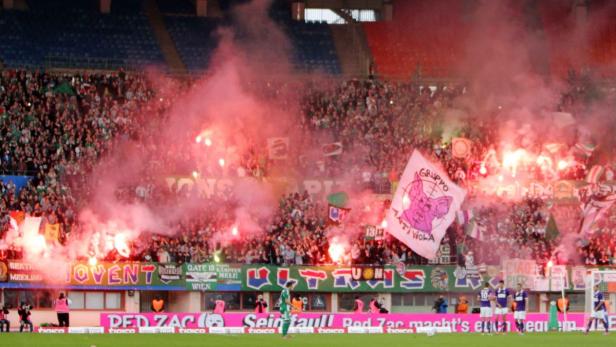 Fußballfans zünden während eines Spiels Bengalos und schwenken Fahnen.