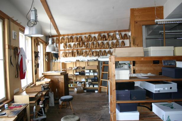 Ein Blick in eine Schuhmacherwerkstatt mit Werkzeugen, Leisten und Schuhkartons.