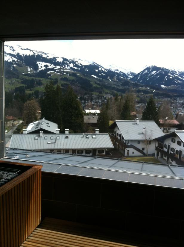 Blick aus einem Fenster auf Häuser und schneebedeckte Berge.