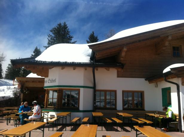 Gäste sitzen auf der Terrasse eines Restaurants im Schnee.