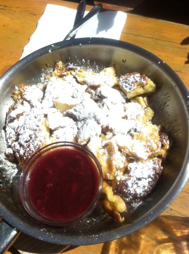 Kaiserschmarrn mit Puderzucker und Apfelmus in einer Pfanne.