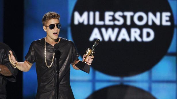 Justin Bieber hält eine Auszeichnung bei einer Preisverleihung in der Hand.
