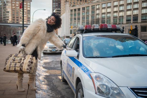Eine Frau in einem Pelzmantel spricht mit einem Polizisten in einem Streifenwagen in der Stadt.