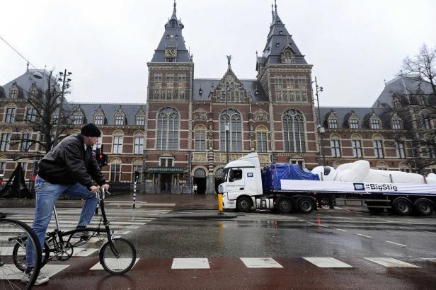 Ein Mann fährt mit einem Klapprad vor dem Rijksmuseum in Amsterdam.