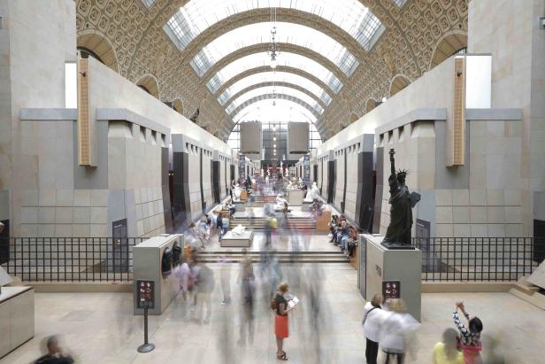 Im Musée d'Orsay betrachten Besucher Kunstwerke, darunter eine Freiheitsstatue.