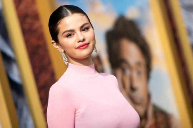 Selena Gomez trägt ein rosa Oberteil und baumelnde Ohrringe.