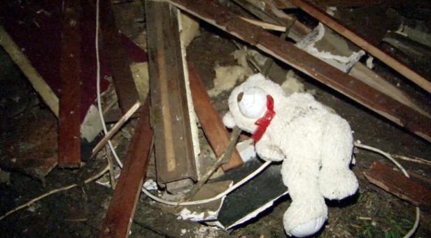 Ein weißer Teddybär liegt inmitten von Trümmern.