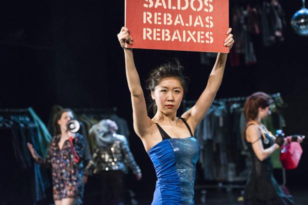 Eine Frau hält ein Schild mit der Aufschrift „Saldos Rebajas Rebaixes“ hoch.